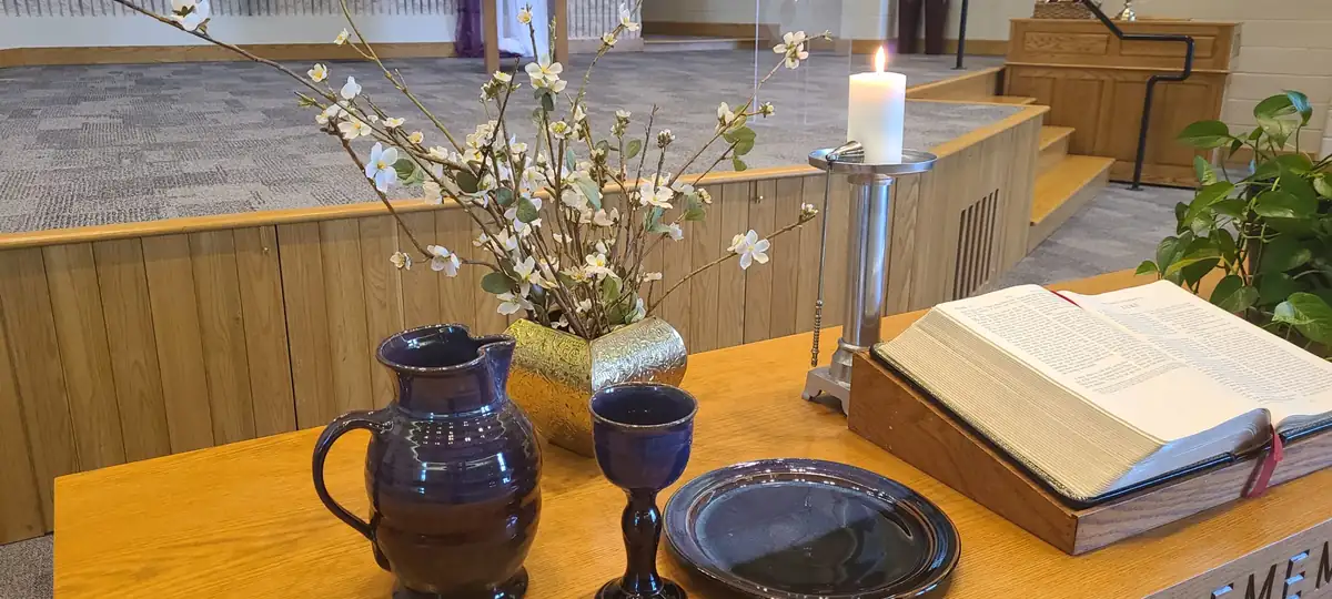 Bethel's communion table set with spring blossoms, an open Bible and pottery.
